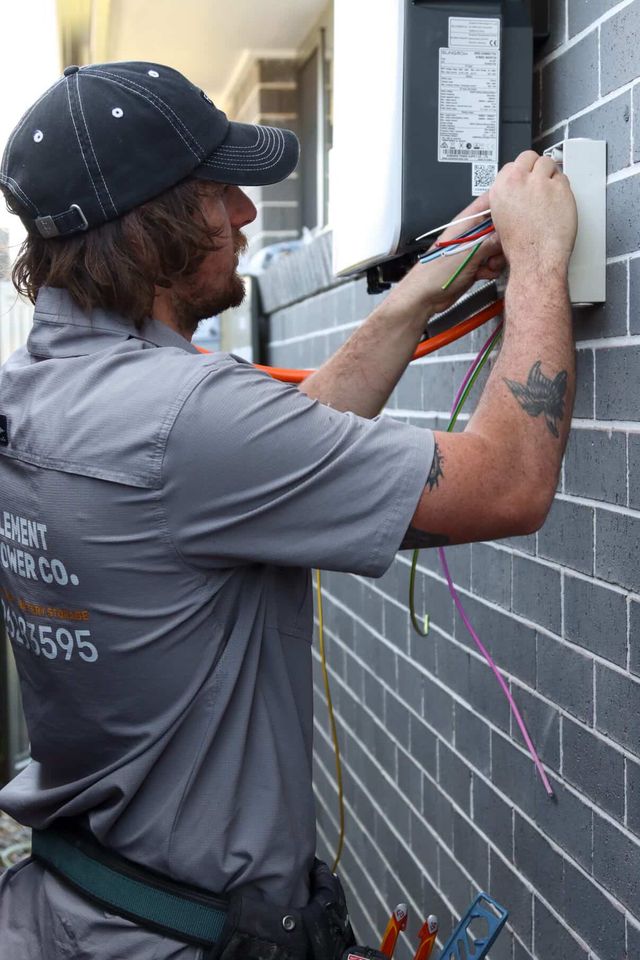 Closeup of an electrician wiring a hybrid inverter on a brick wall